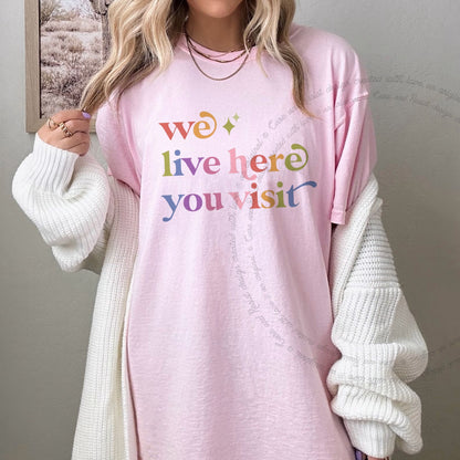 We Live Here You Visit Care & Resist rainbow tee