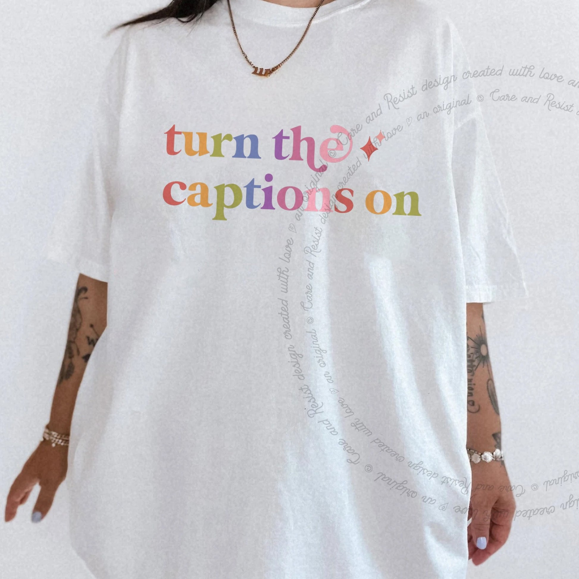Turn the Captions on Care & Resist rainbow tee