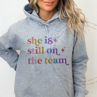 She is Still on the Team Care & Resist Gildan hoodie in Sport Grey