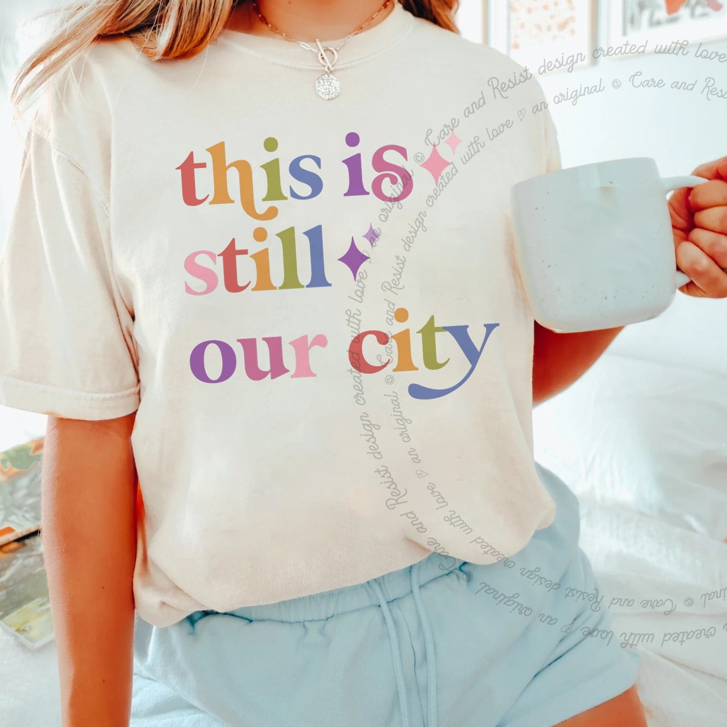This is Still Our City Care & Resist rainbow tee
